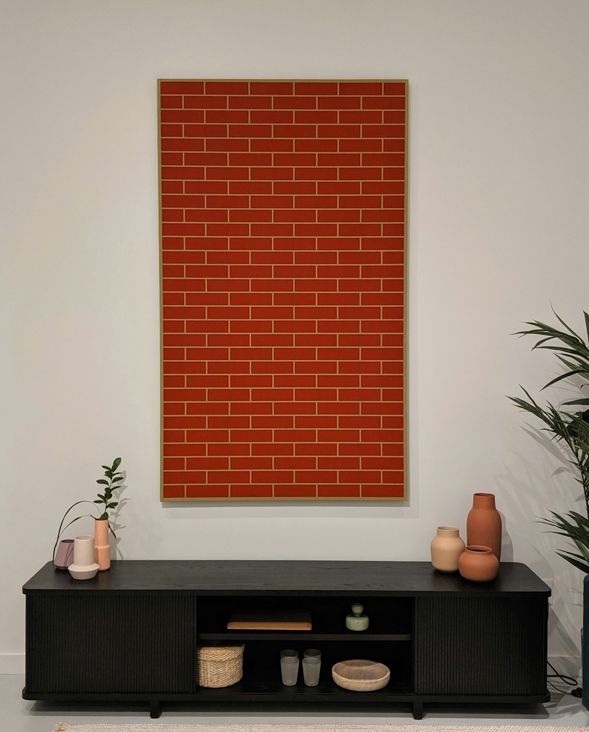 Des vases en céramique reposent sur une console en bois sous une œuvre d'art rouge.