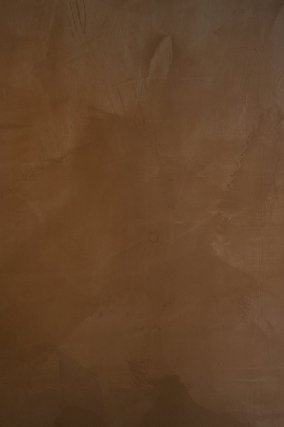 Gros plan d'une surface murale texturée en microciment brun.